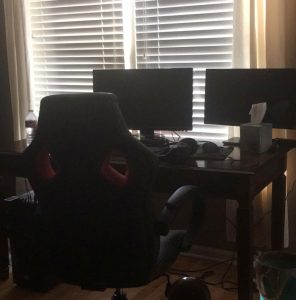 A computer desk with two large monitors and a gaming chair