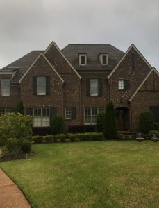 A large three-story house with a big green front yard.
