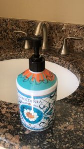 A pump-bottle of soap sits in front of a bathroom sink